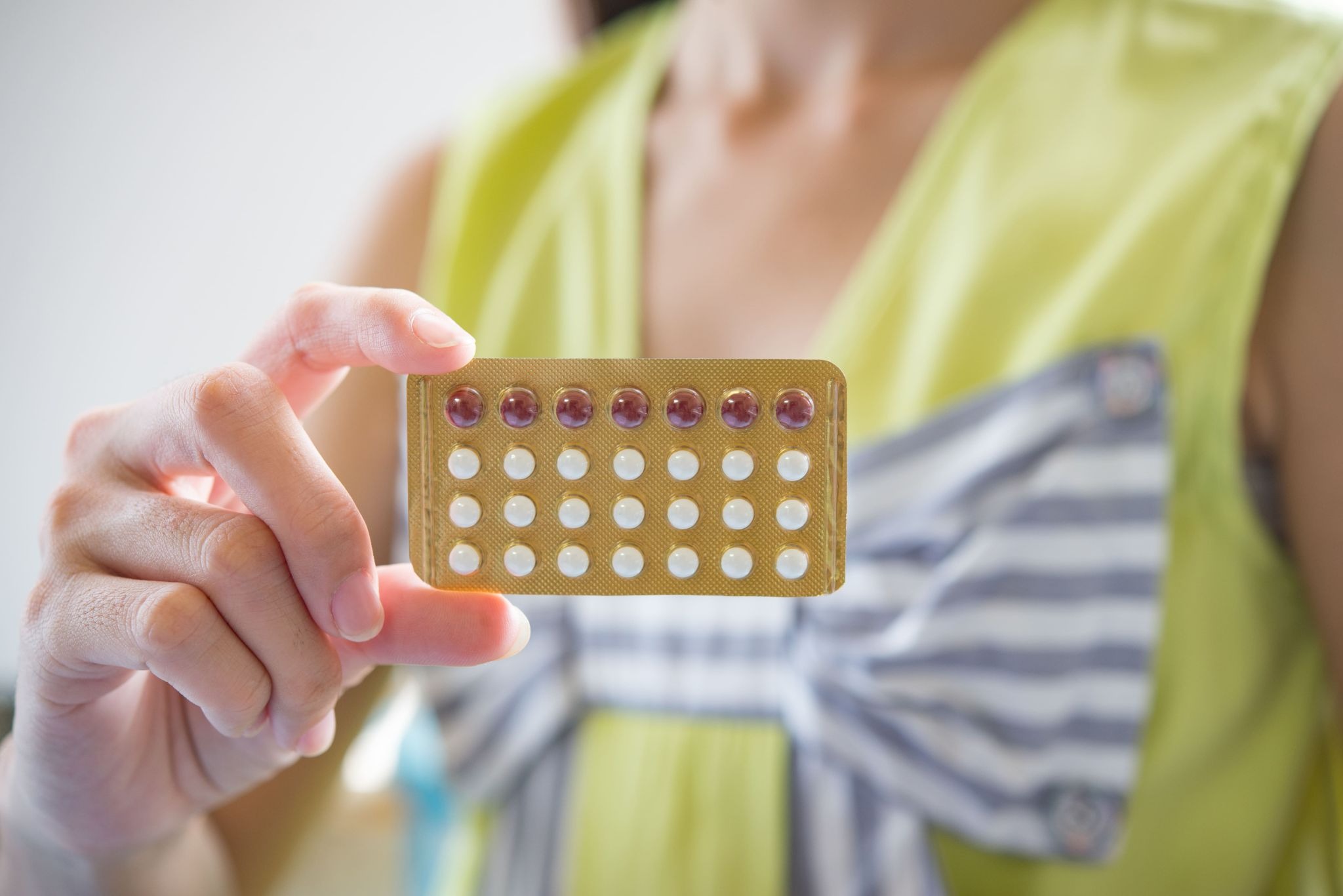 showing contraceptive pills on yellow shirt 
