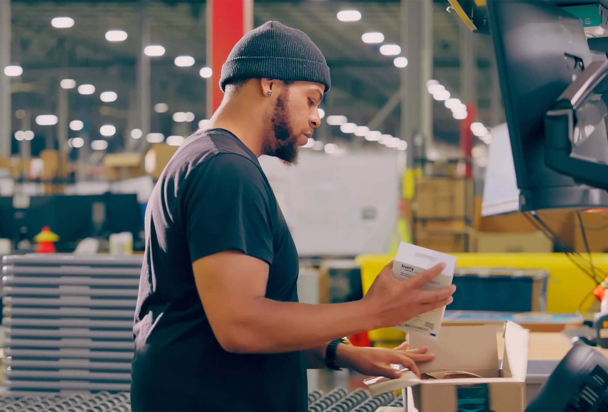 Warehouse worker checking a packaged item at a workstation.