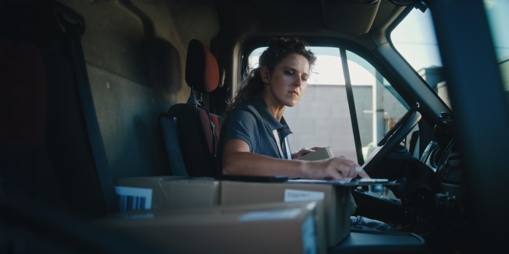 Delivery driver using a laptop inside a vehicle.