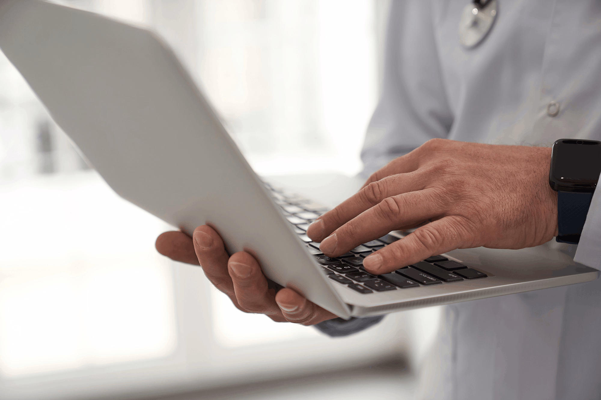 Close up cropped head of general practitioner typing on notebook while standing during working day