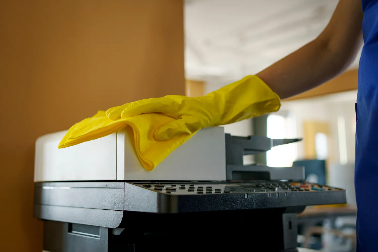 Gelber Handschuh reinigt Drucker in blauer Uniform