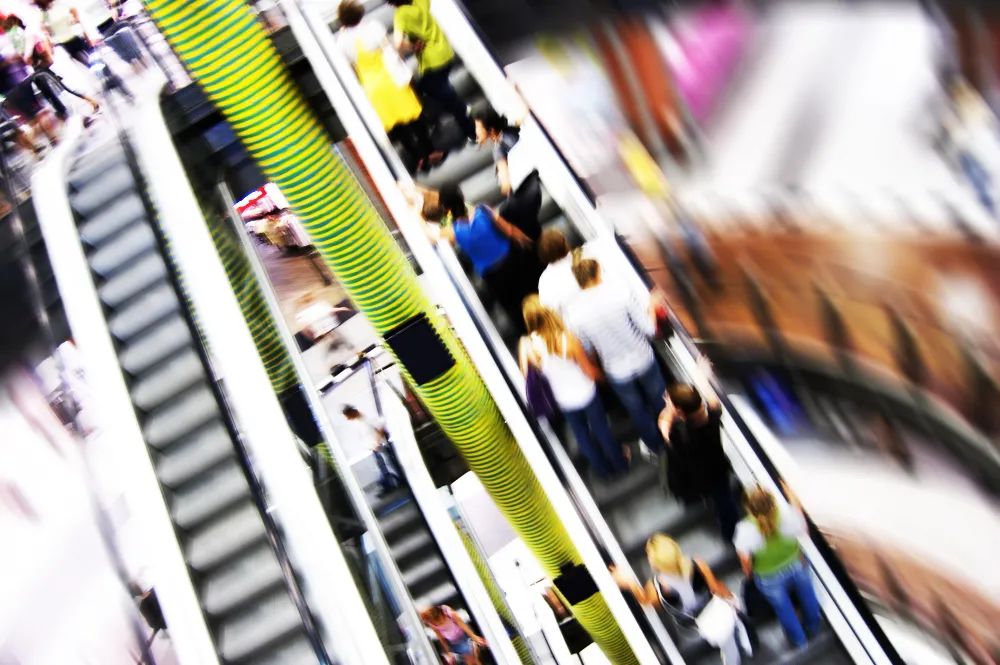 Blick auf belebte Messehalle mit Rolltreppen und Besuchern – Fokus auf gepflegte und saubere Veranstaltungsflächen.