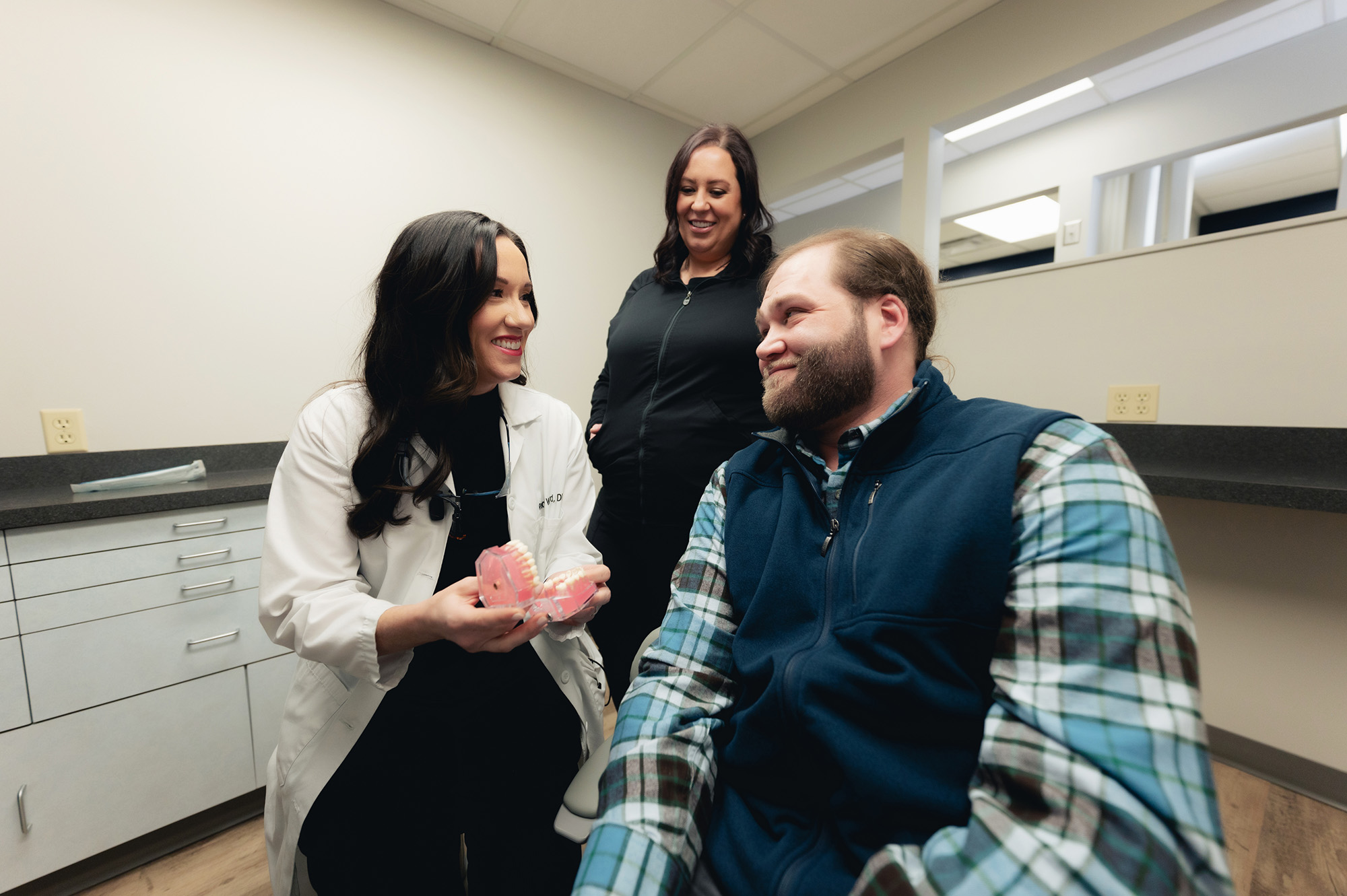 Photo of Dr. ward talking to a male patient in a chair, smiling