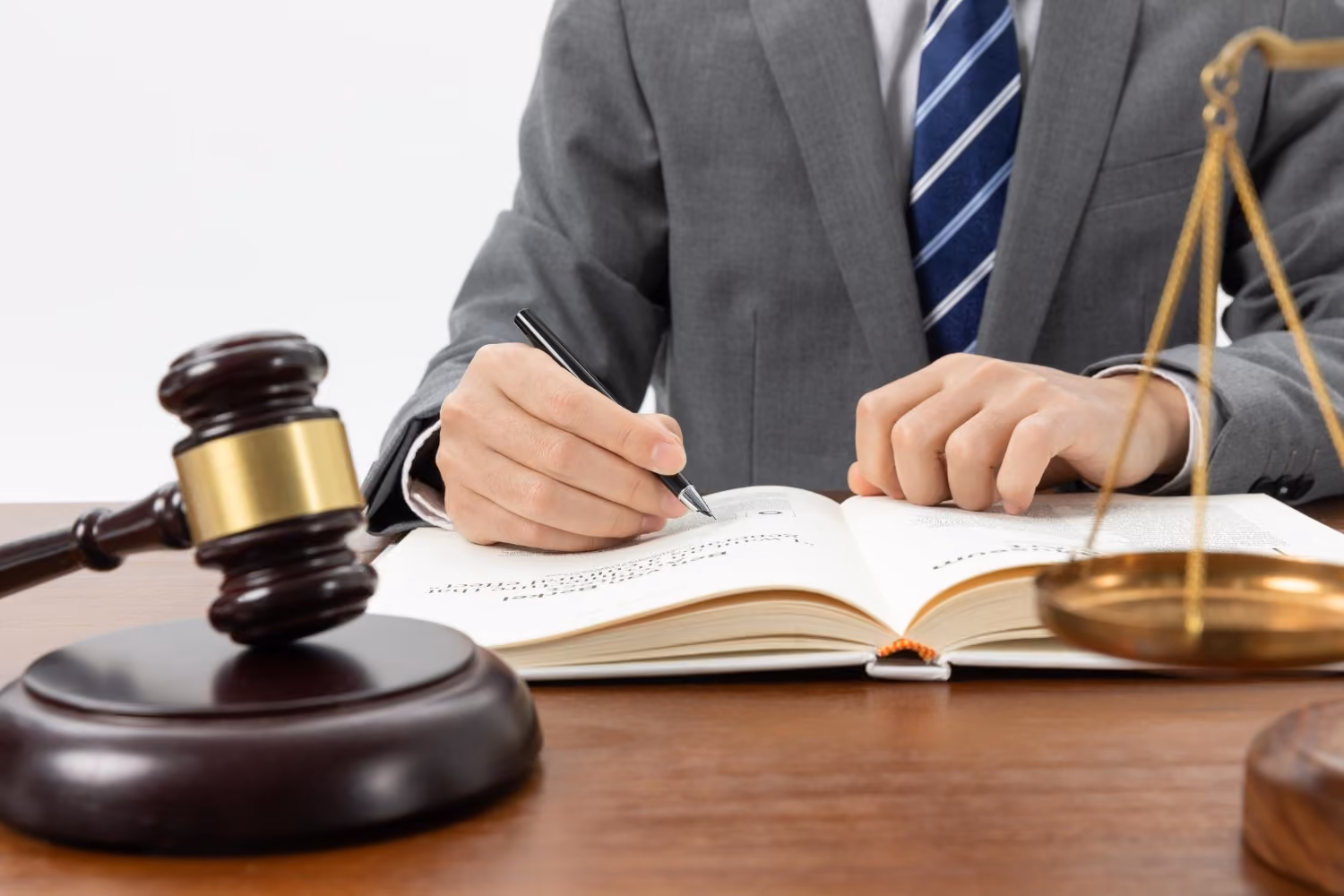 Lawyer writing in law book with gavel and scales