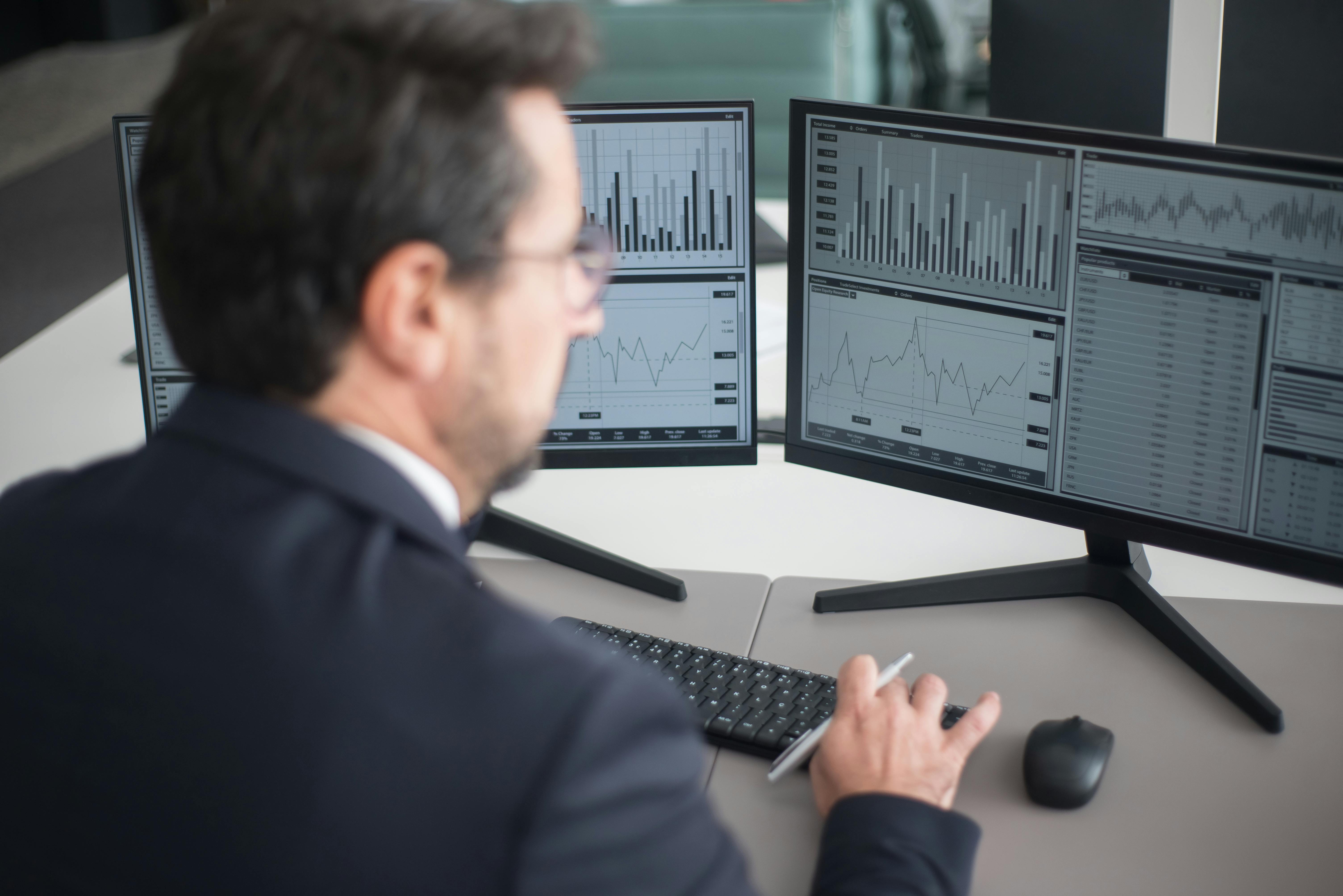 Businessman analyzing financial charts on computer monitors