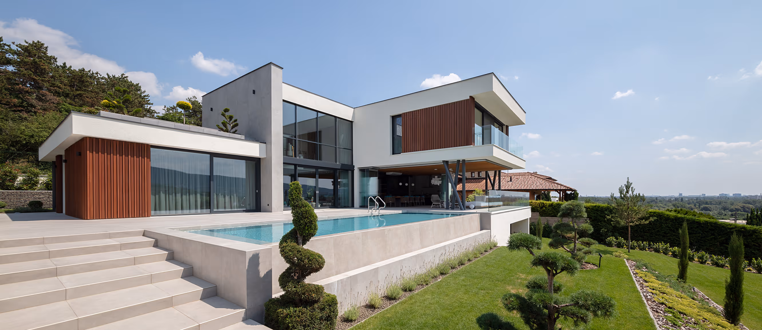 Modern villa with manicured garden and pool with blue sky in the background