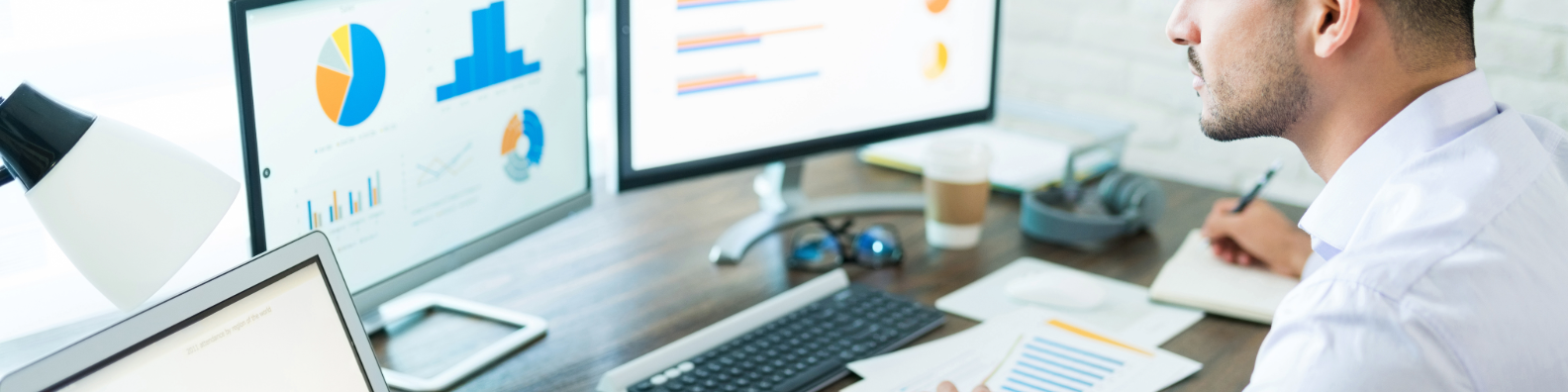 Business analyst working with data visualization charts on multiple monitors