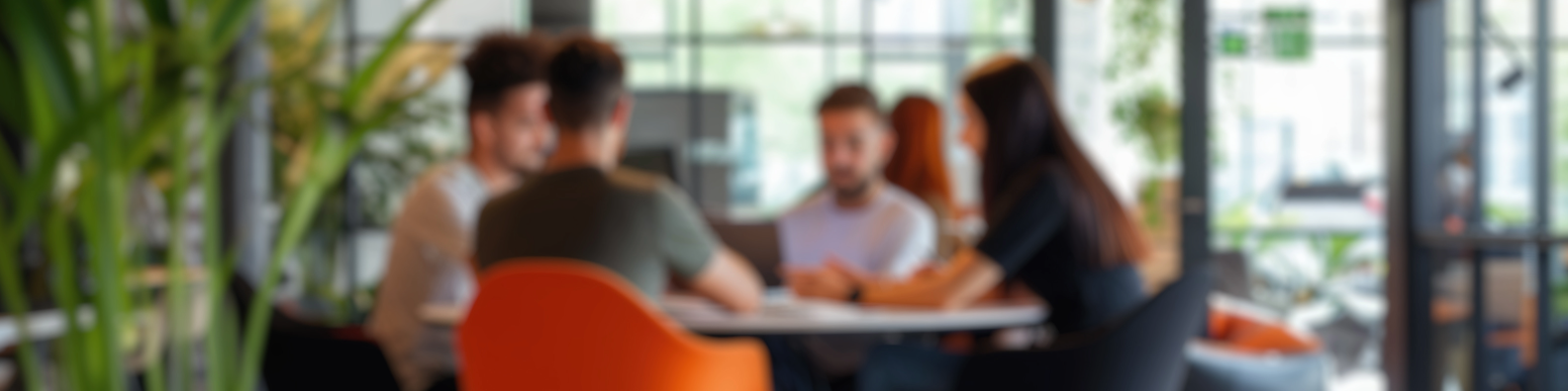 Blurred group meeting in modern office with orange chairs and plants