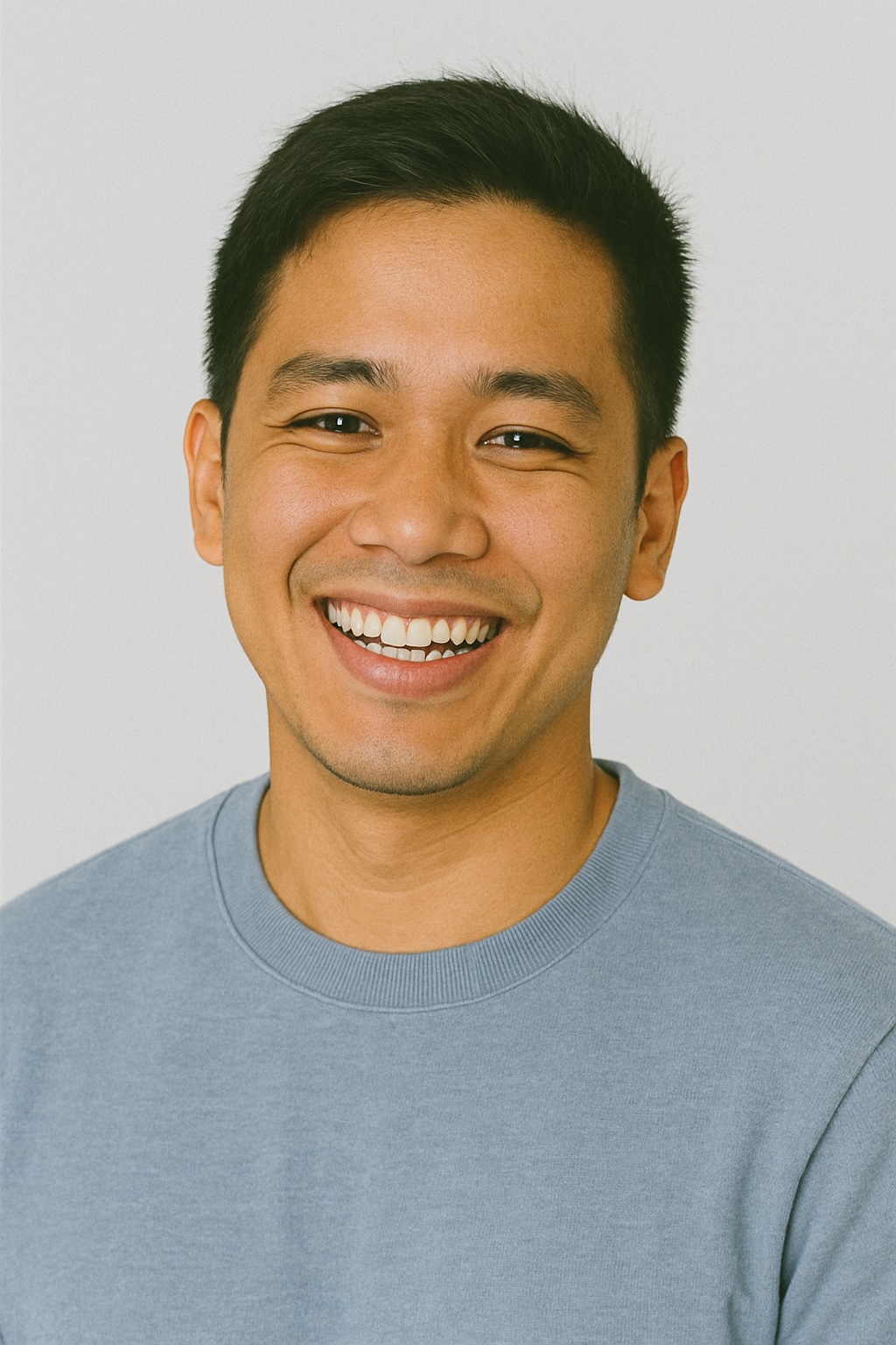 A person in a blue shirt smiling brightly with genuine happiness