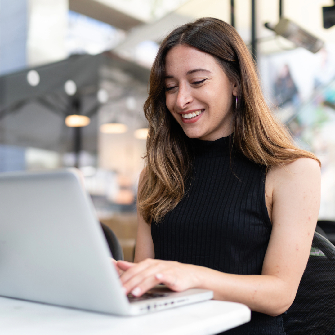 Smiling woman working on laptop in modern office or coworking space