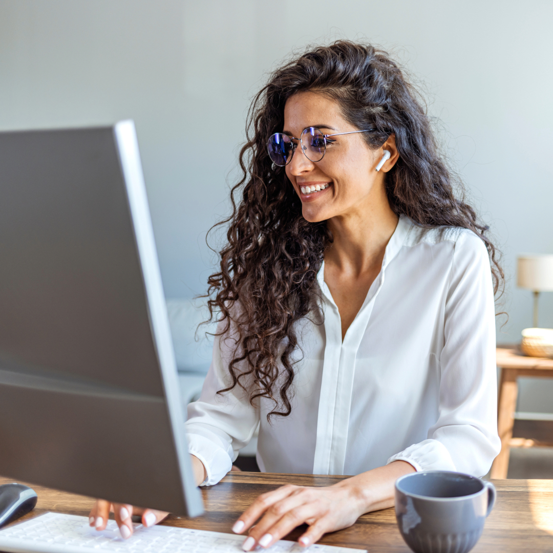 Smiling woman working on laptop at home with coffee mug nearby
