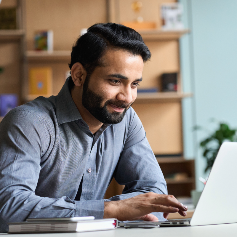 Professional working on laptop in modern office with bookshelves