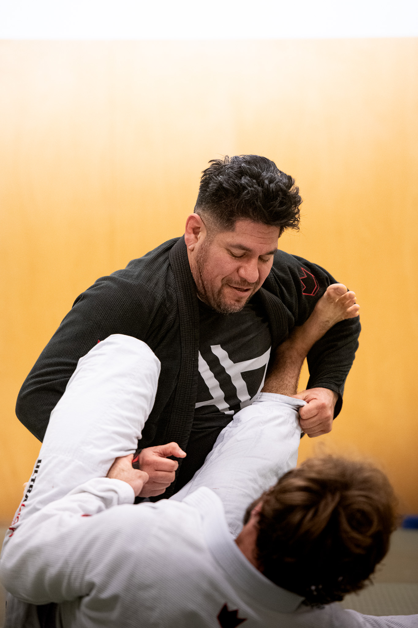 Two men practicing Brazilian Jiu-Jitsu with one man gripping the other's gi and controlling his leg.
