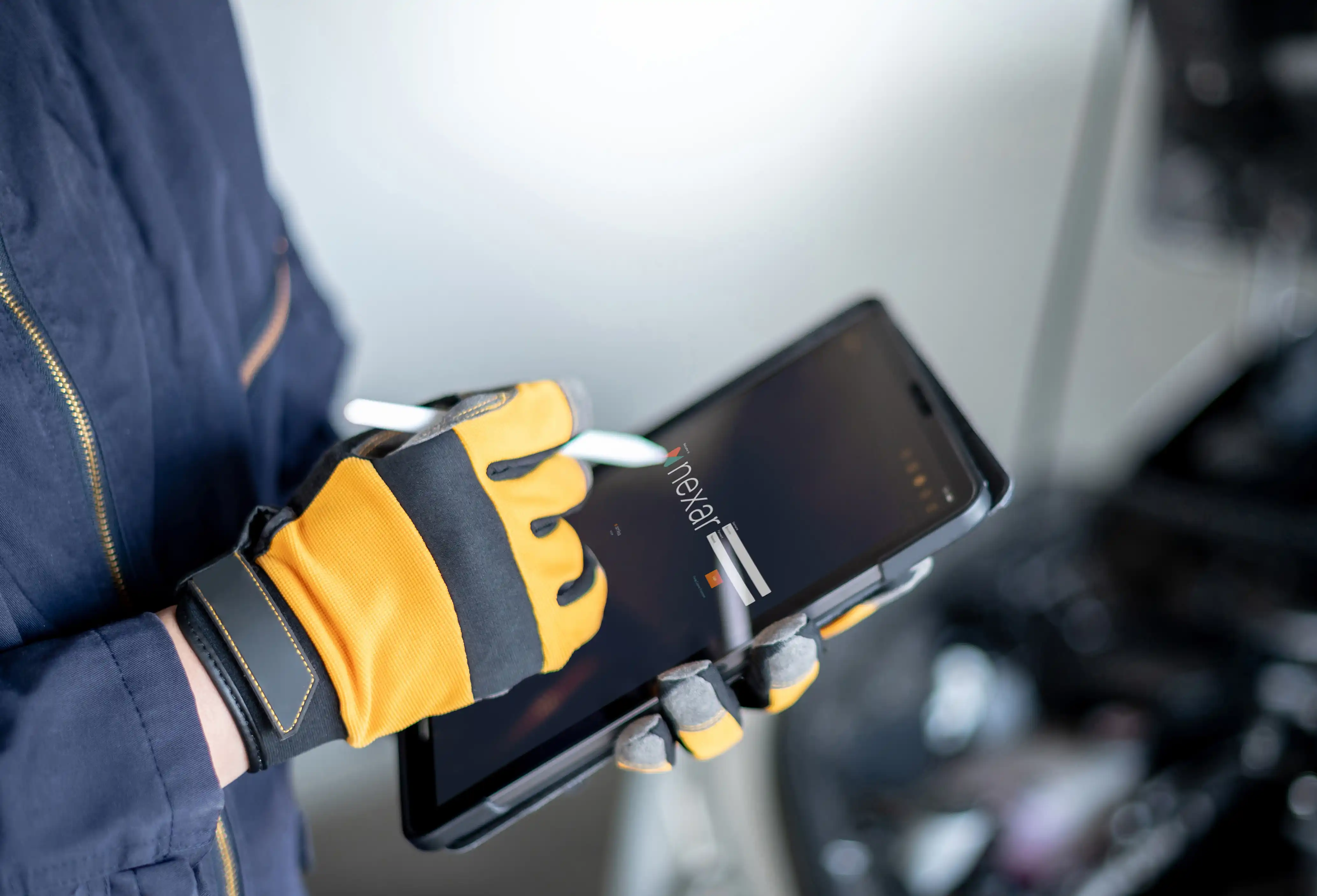 Technician wearing protective gloves using a tablet with Nexar Ex inspection software to carry out digital inspections in a hazardous industrial environment.