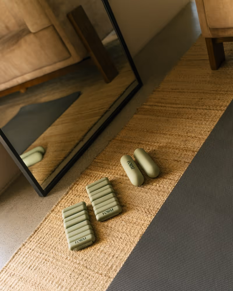 Home wellness setup with light green weights and exercise mat placed in front of a mirror.
