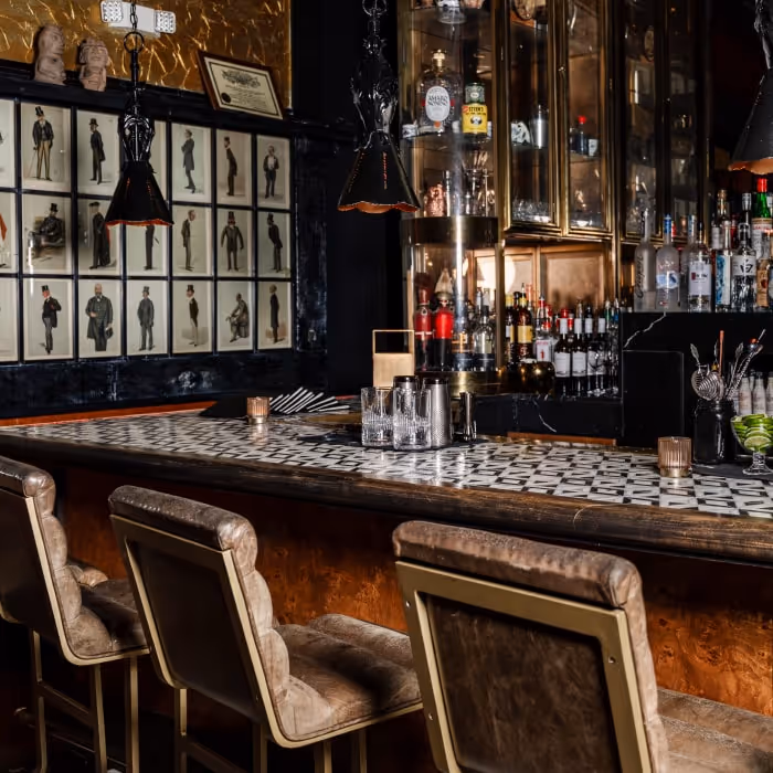 Seymour’s speakeasy-style bar with patterned tile countertop, vintage portraits and leather stools.