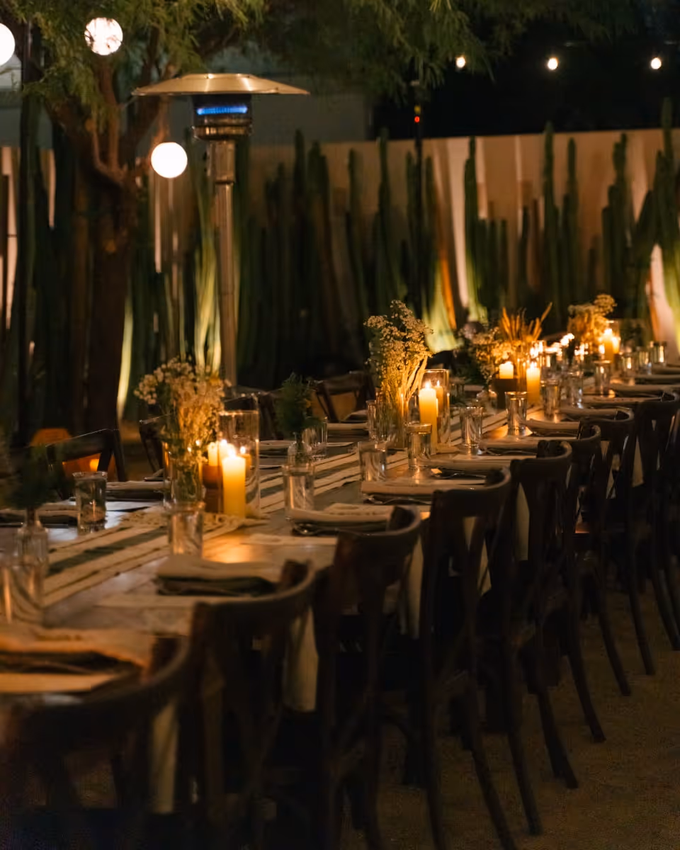 Elegant outdoor dining setup with long candlelit tables under string lights in desert setting