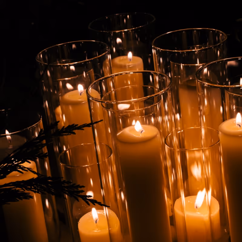 Close-up of glowing candles in tall glass holders creating warm evening ambiance