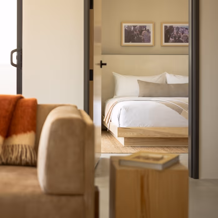 Interior view of hotel suite with sofa, wooden side table, and doorway into bedroom.