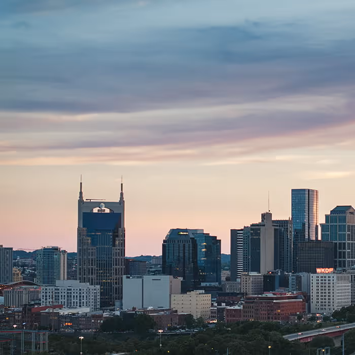 Nashville skyline at sunset featuring the iconic AT&T Building and downtown skyscrapers with WKDF sign under pastel sky