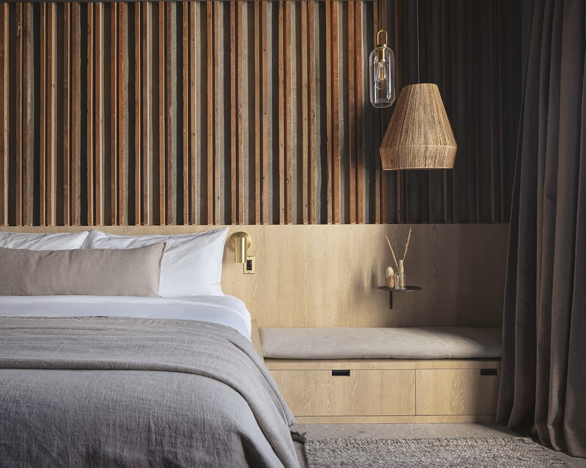 Minimalist bedroom design with rustic wood slat wall panels, natural fiber pendant lamp, brass sconces, and neutral bedding