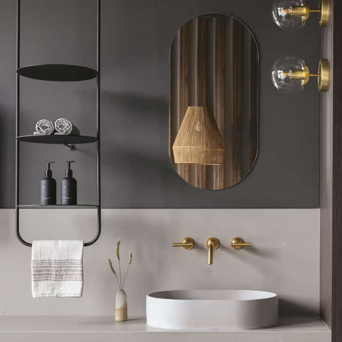 Contemporary spa bathroom vanity with oval mirror, brass wall-mount faucet, vessel sink, and minimalist black metal shelving