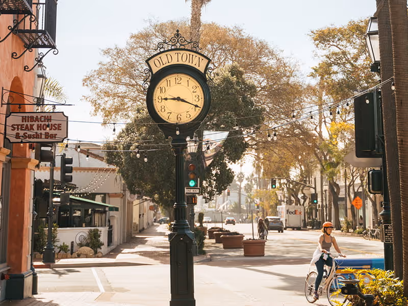 Old Town vintage street clock on State Street with string lights, Hibachi Steak House sign, and cyclist in downtown Santa