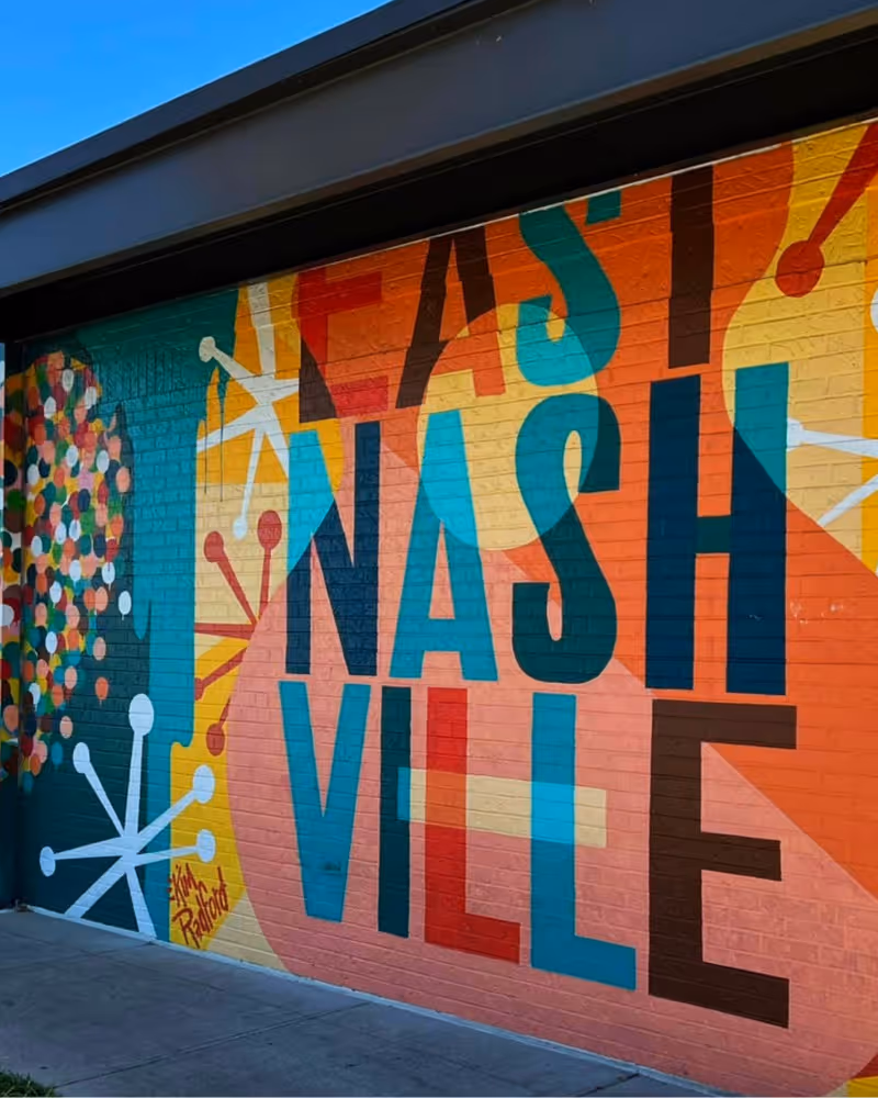 Colorful street mural reading "East Nashville" with mid-century atomic designs and vibrant orange, teal, and yellow hues.