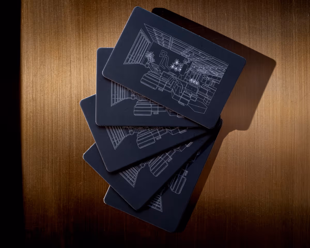 Fanned stack of dark navy key cards with white architectural line drawings displayed on a warm brushed gold surface.