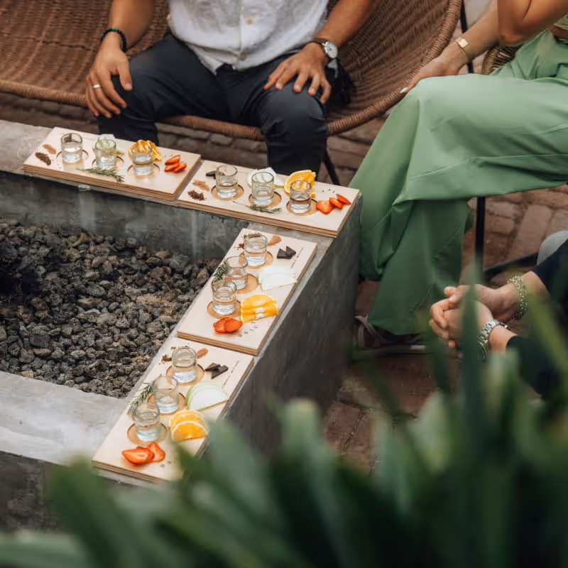 Tequila or mezcal tasting flight boards with shot glasses, orange slices, strawberries, and chocolate arranged around