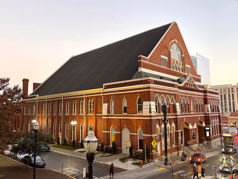 The historic Ryman Auditorium in Nashville at dusk, showcasing its iconic red brick Gothic Revival architecture and arched