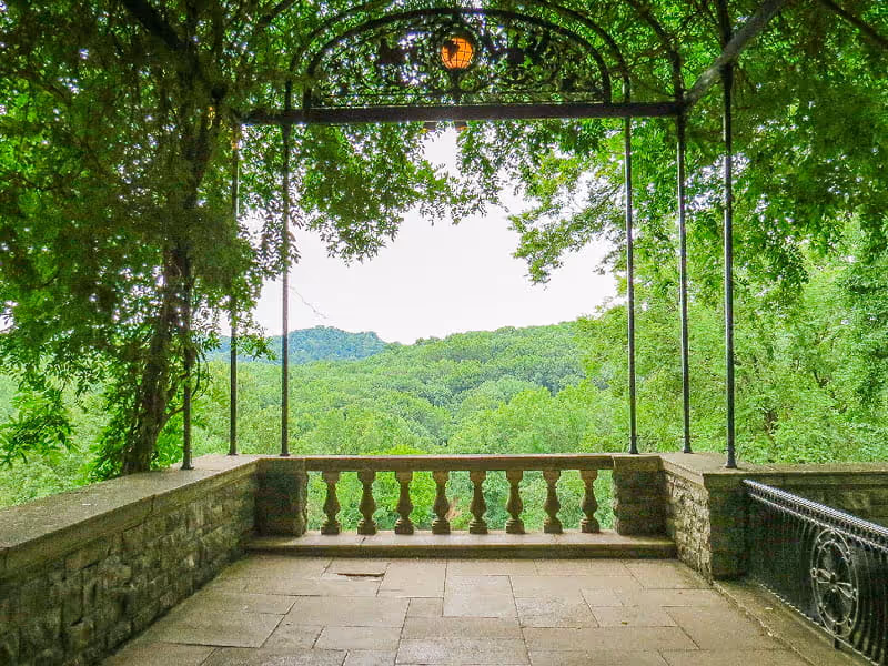 Vine-covered stone balcony overlook with balusters framing a panoramic view of lush green forested Tennessee hills.