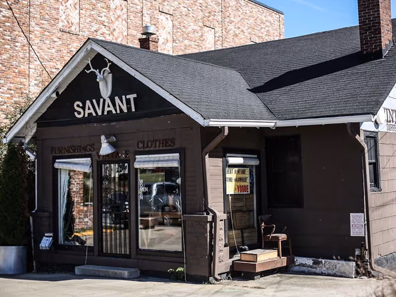 Savant vintage store exterior in a brown building advertising furnishings and clothes, with a deer skull logo above
