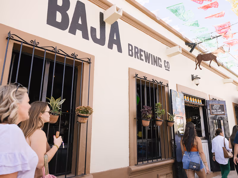 Outdoor beer garden at Baja Brewing Company with white facade and signature signage