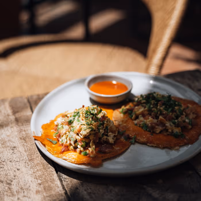 Mexican breakfast plate with scrambled eggs on tostadas served with habanero salsa on a rustic wooden table