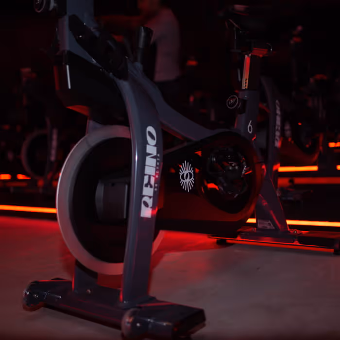 Rhino brand stationary spin bike illuminated by dramatic red lighting in a dark indoor cycling studio setting