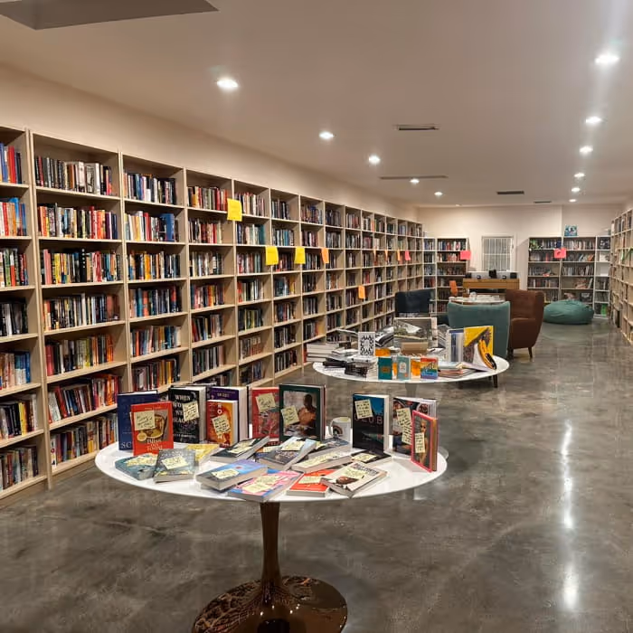Spacious independent bookstore with floor-to-ceiling shelves and curated book displays on round tables