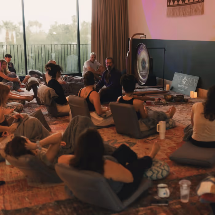 Group meditation and sound bath session at The Den Meditation studio with a large gong and singing bowls