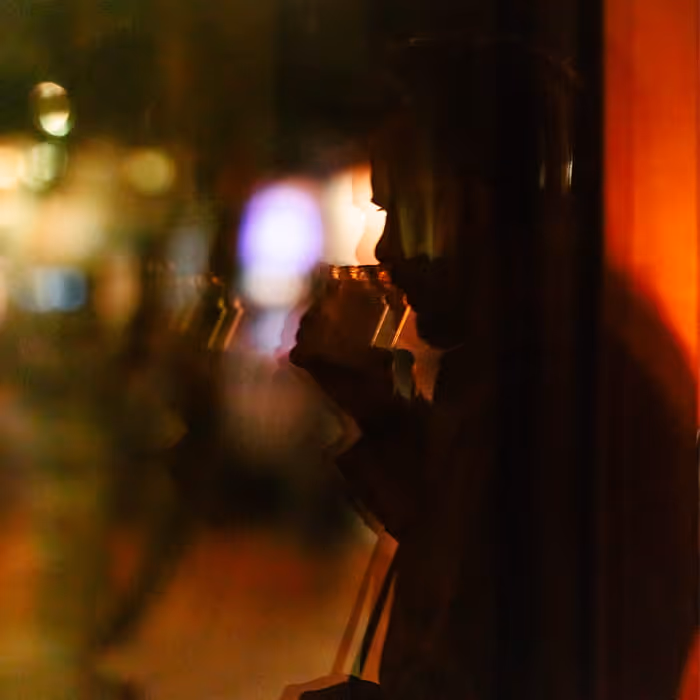 Silhouette of a person's profile reflected in a window at night with colorful bokeh city lights in the background