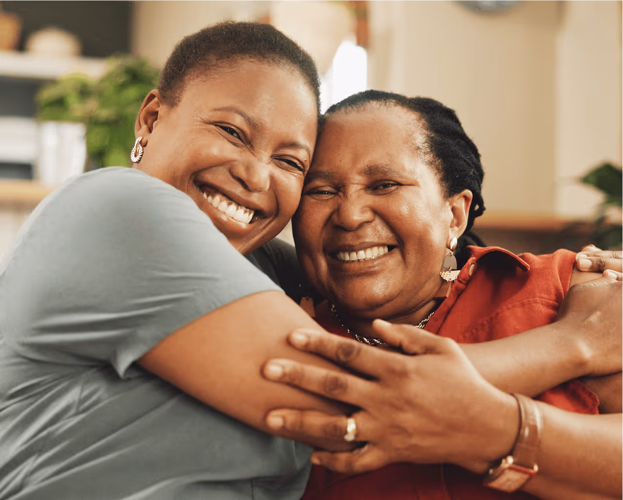 Two women, one mature and one younger, smiling and hugging each other warmly