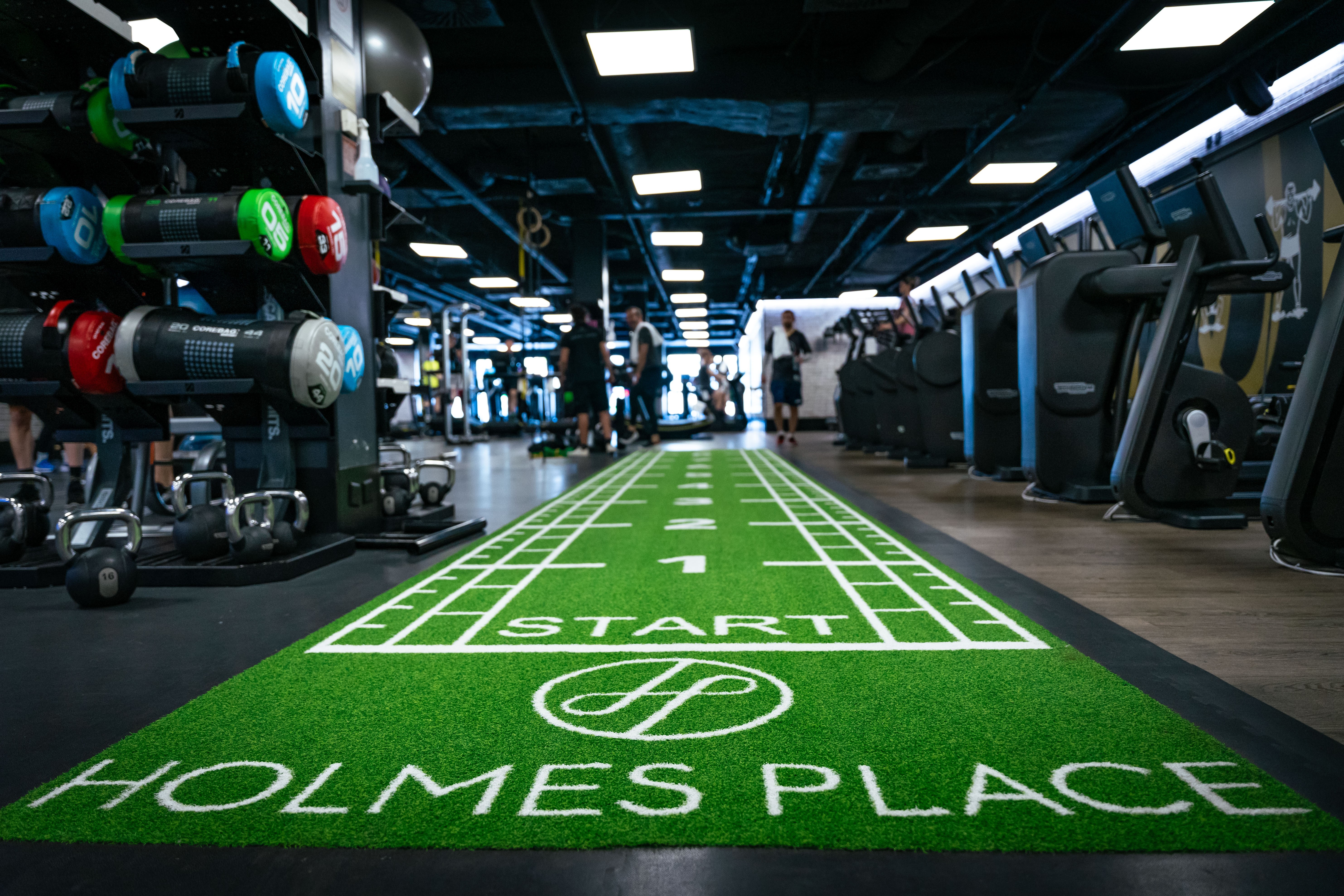 Moderne grüne Laufstrecke mit weißen Markierungen und Holmes Place Logo in Wien.