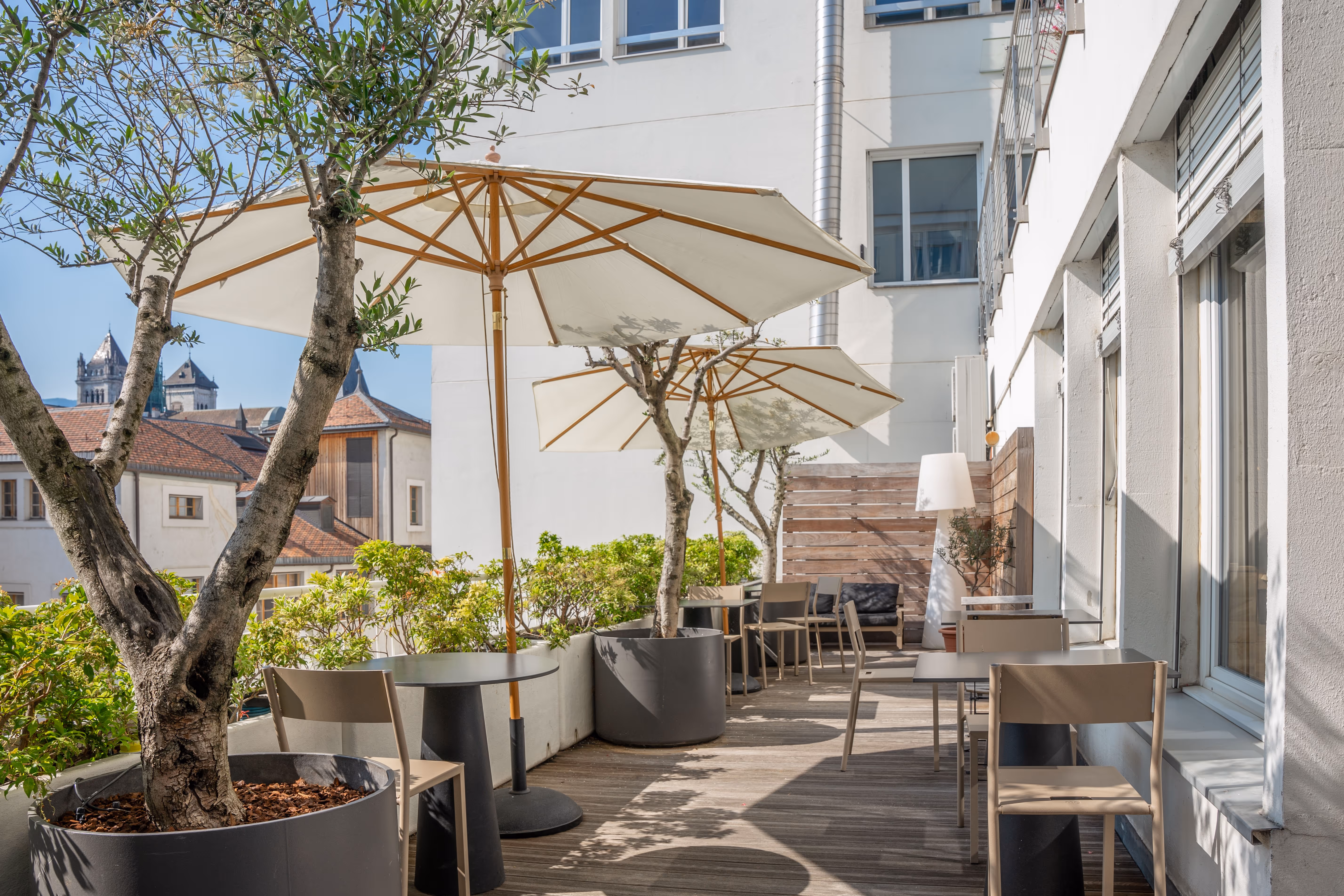 Outdoor-Fitnessbereich mit Sonnenschirmen und Topfbäumen in den Einrichtungen des Holmes Place Wien.