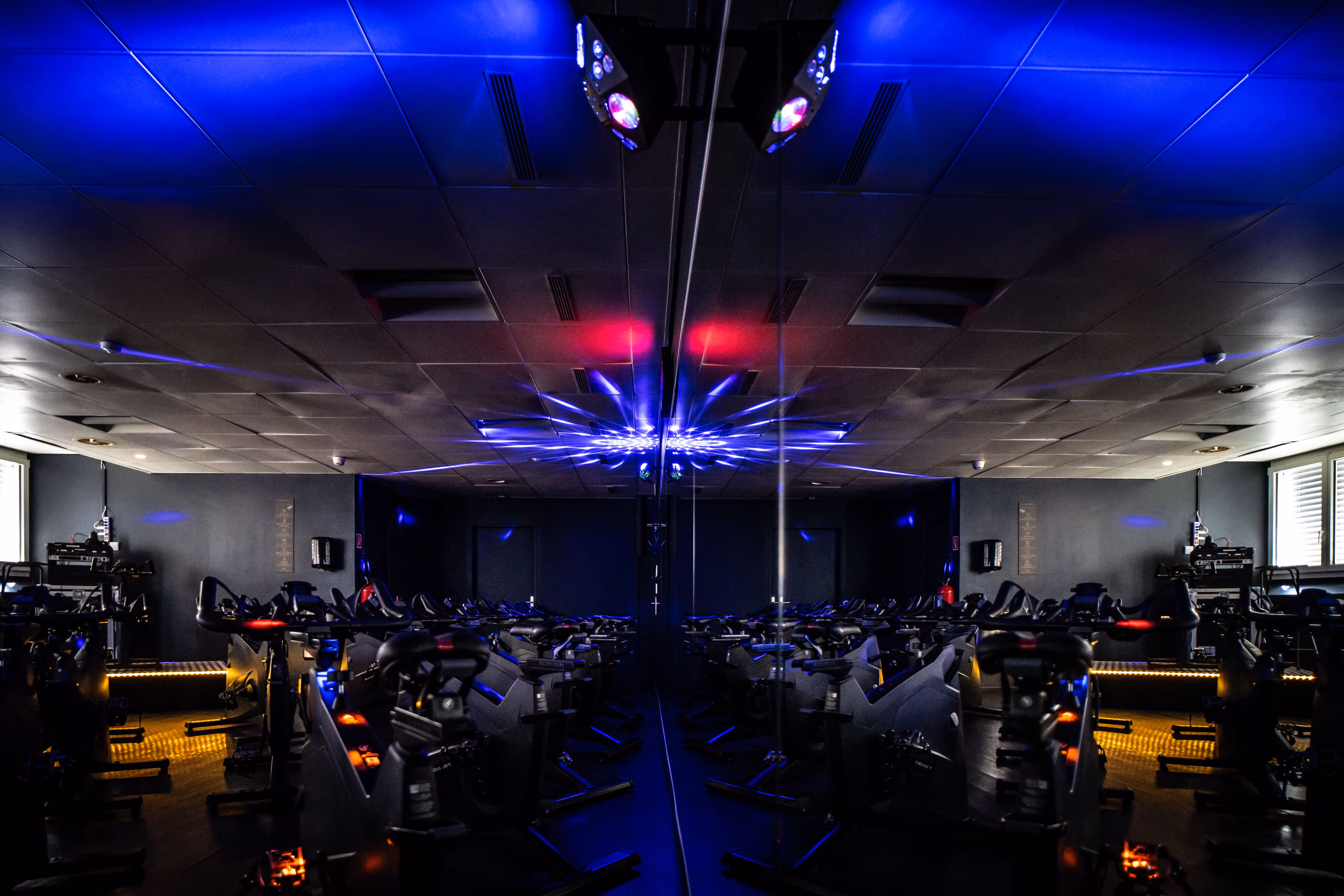 Premium Fitness Studio mit hochmodernen Fahrrädern und lebendigen blau-roten Beleuchtungseffekten.