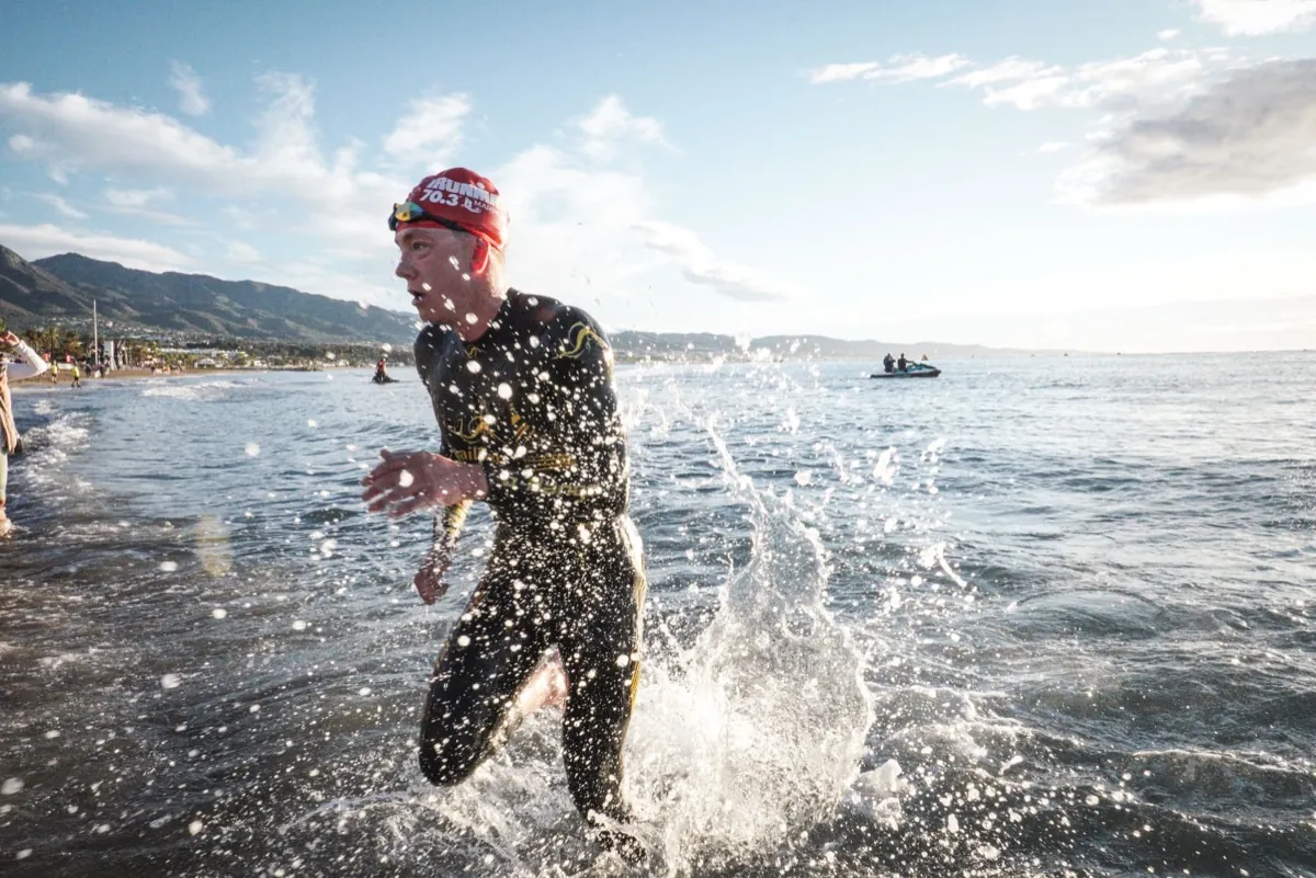 Triathlet im Neoprenanzug läuft aus dem Meer