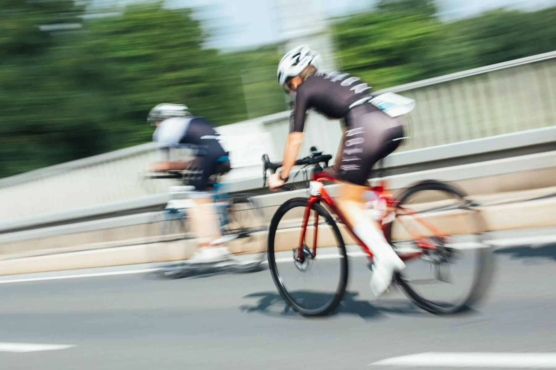 Zwei Radfahrer in Bewegung auf einer Straße, Hintergrund verwischt
