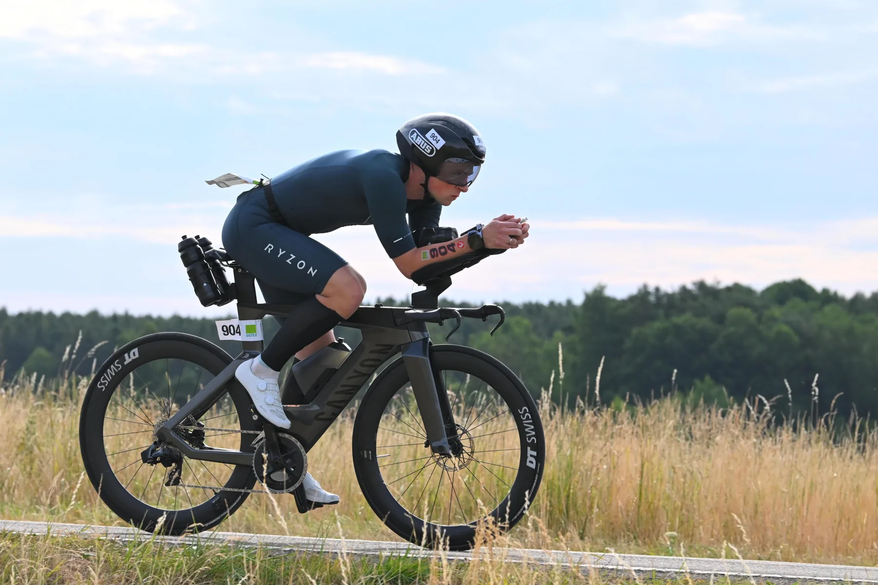 Triathlet in Aeroposition auf dem Zeitfahrrad vor einem Feld