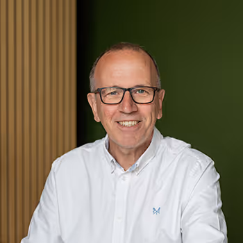 Smiling older professional in white shirt and glasses against green background