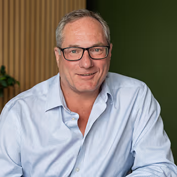 Smiling middle-aged professional in glasses and light blue button-up shirt