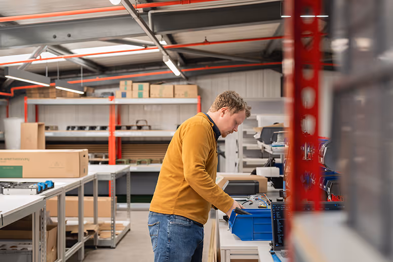 Worker in yellow sweater sorting items in industrial warehouse storage area