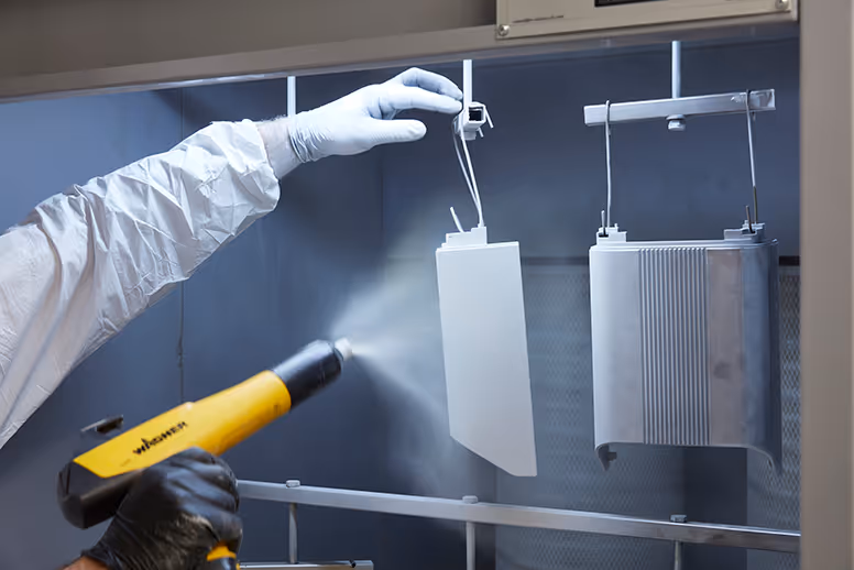 Gloved hand using spray gun in industrial powder coating process